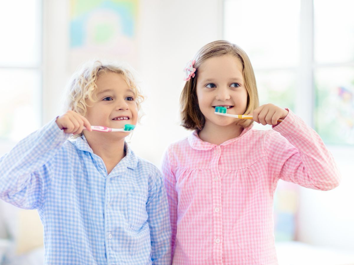 Two children using toothpaste while brushing their teeth