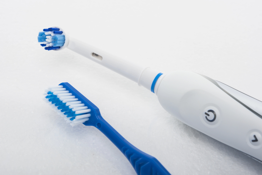 Manual toothbrush beside an electric toothbrush, comparing two options for daily oral hygiene.