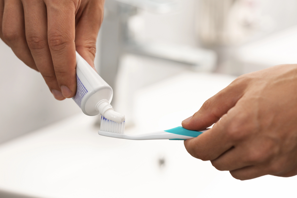 Toothpaste being applied to a toothbrush as part of a whitening oral care routine.