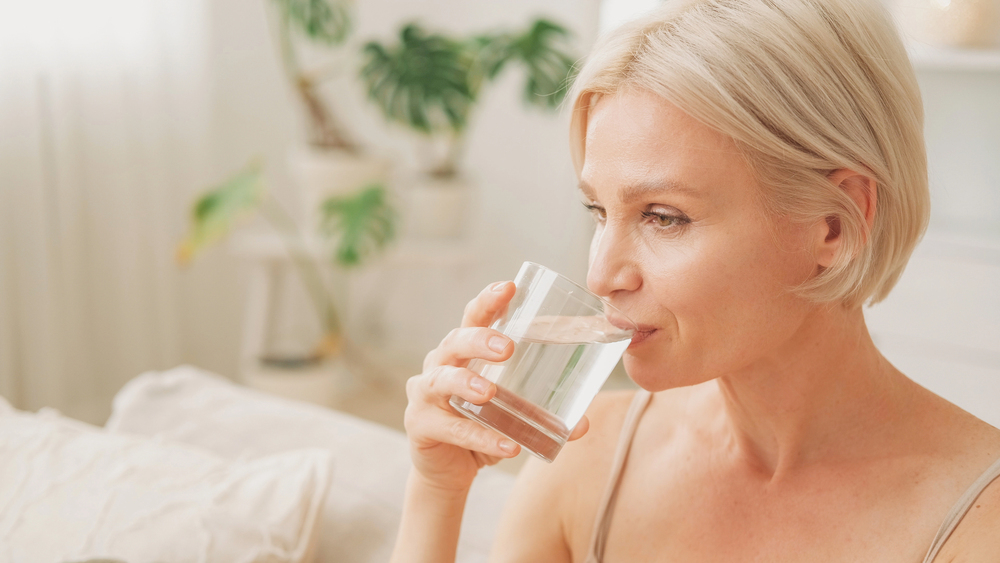 Woman drinking water to help manage dry mouth and support oral health