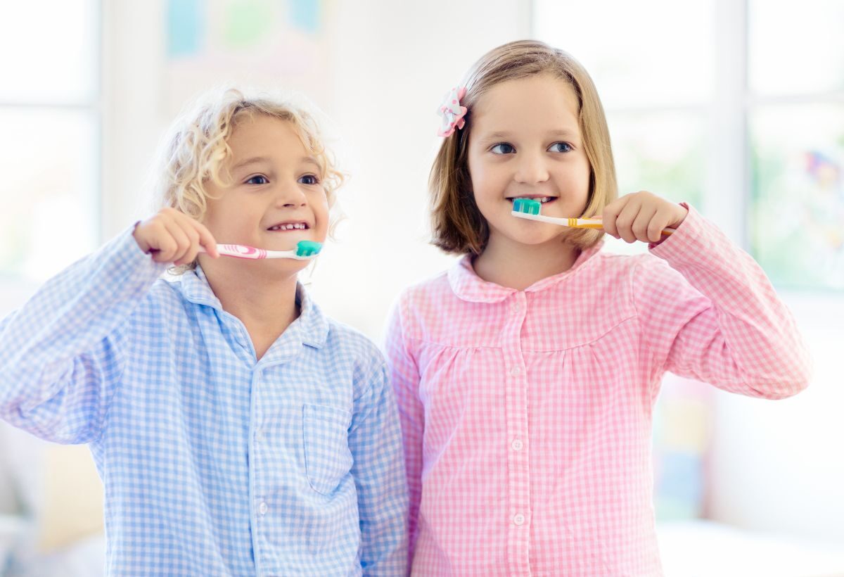 Two children brushing their teeth with manual toothbrushes and toothpaste