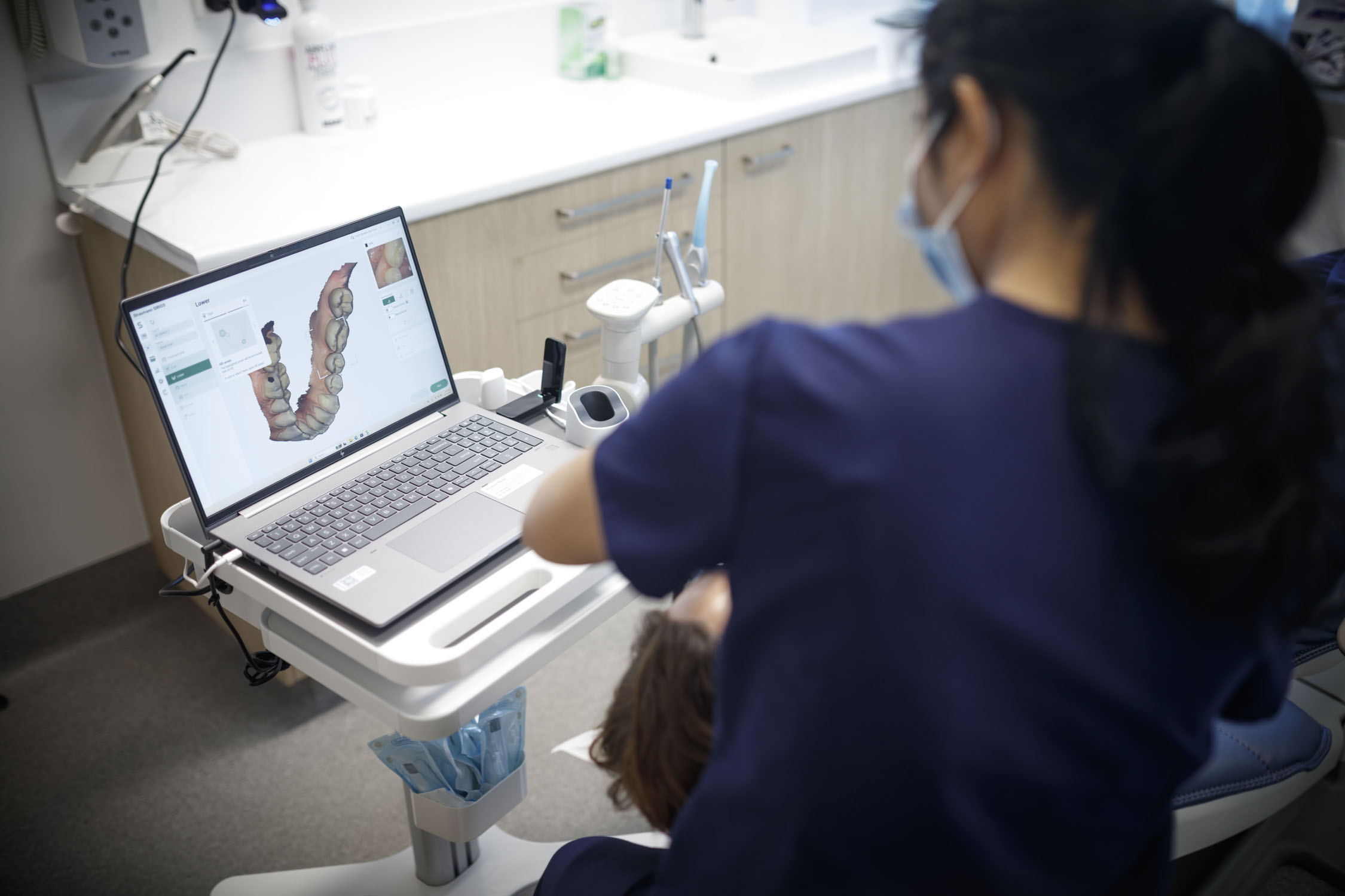 A dental professional reviews a patient’s 3D dental scan of Crowns & Bridges on a laptop in a modern clinic.