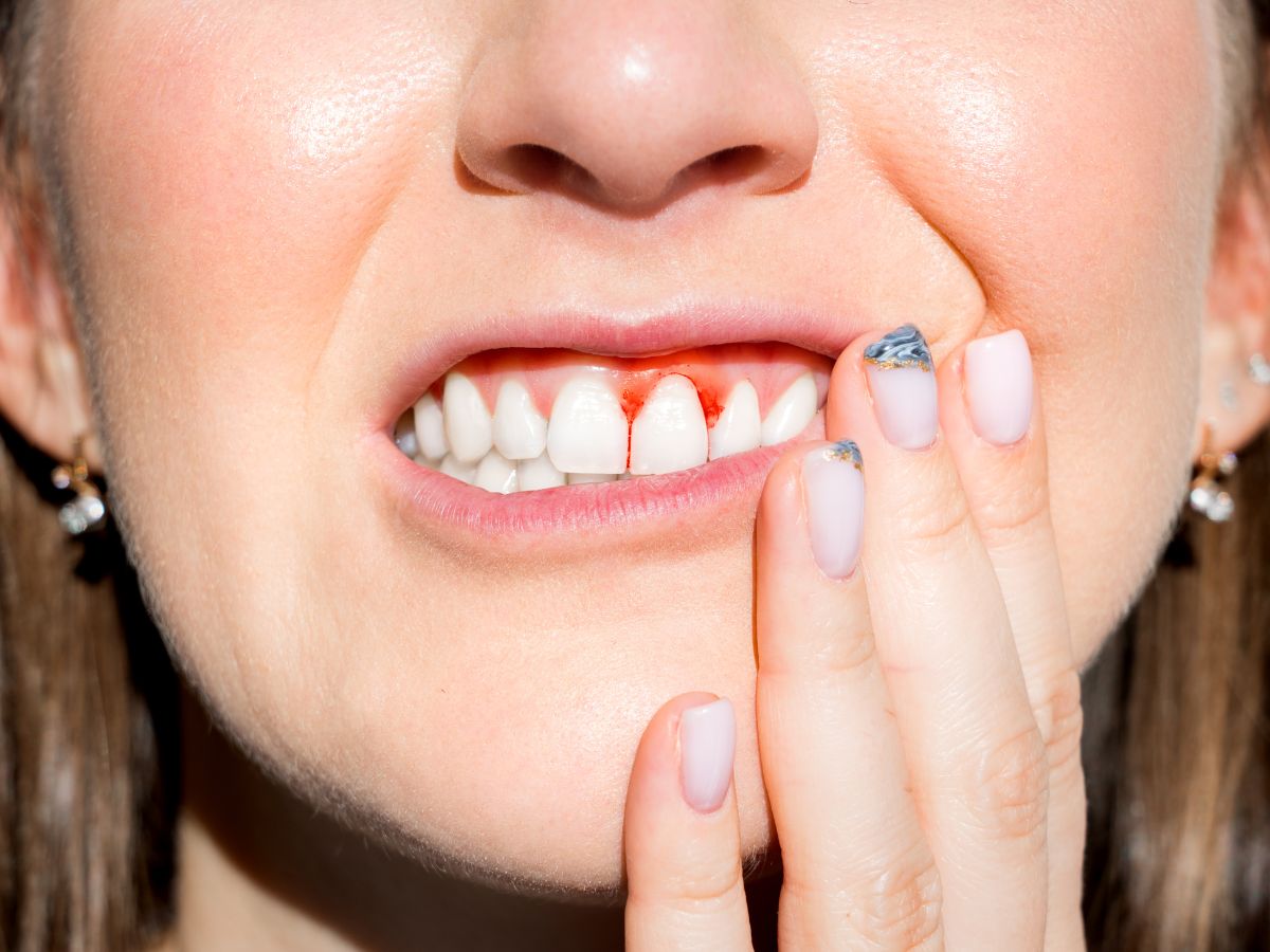 Close-up of person touching bleeding gums, a common warning sign of gum disease