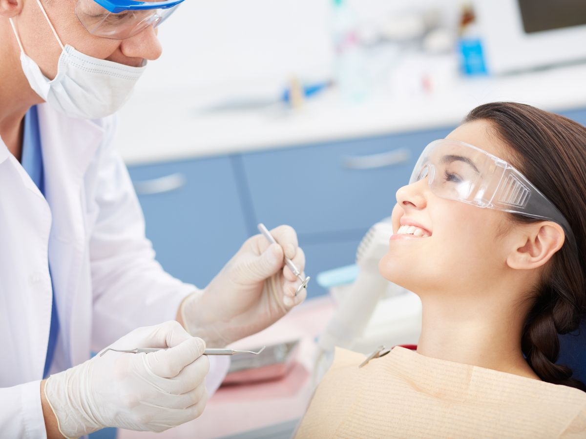Dentist in mask and gloves uses dental tools on a patient in a clinic during a checkup or procedure