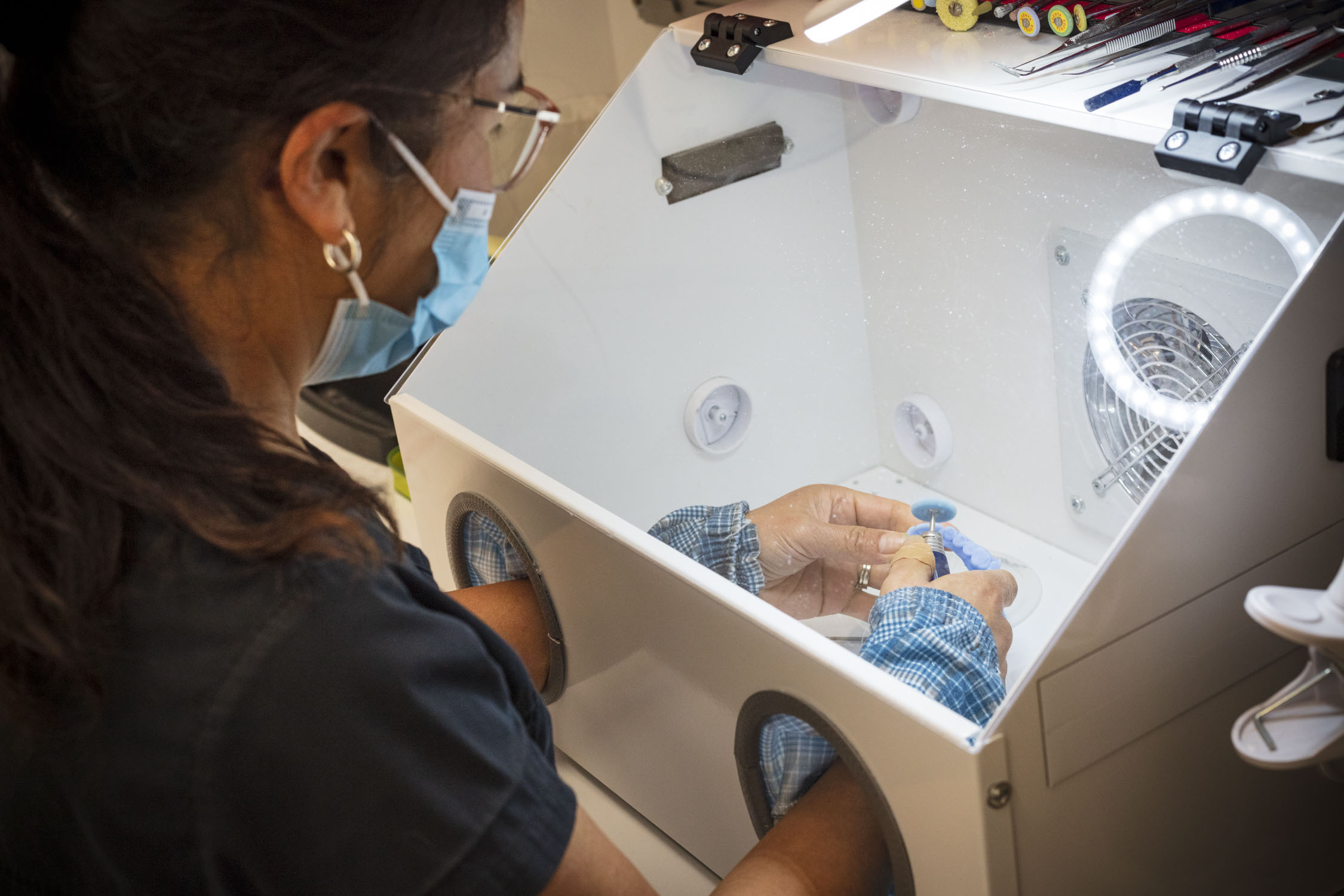 Person with mask and gloves works on a small object in lab glove box, preparing Tooth Sparkler for kit use.