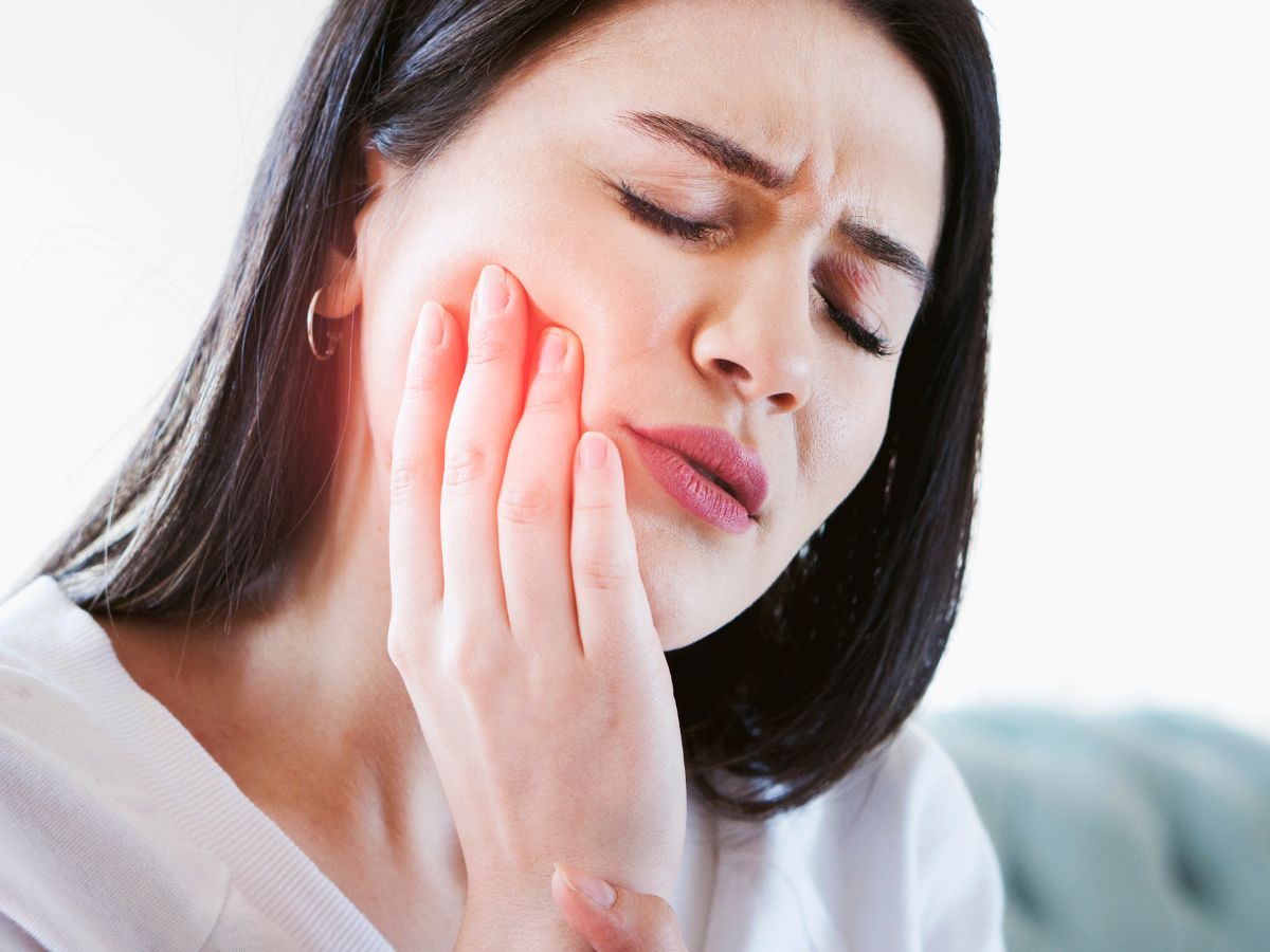 Person holding their cheek while experiencing tooth pain